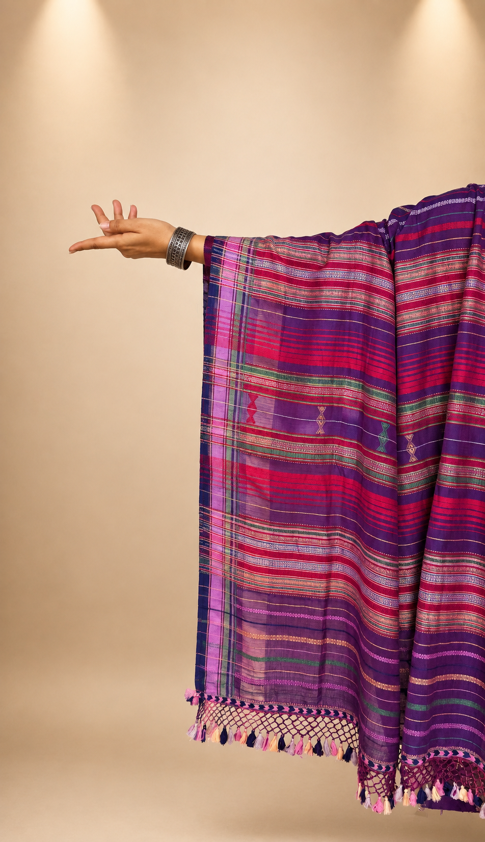 A close-up of a draped bhujodi saree pallu in a deep purple colour with a striped body. The palla has playful tassels.